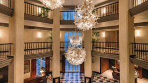 A multi-level hotel lobby with a checkered floor, large chandeliers, and a view of the outside through a large window. - Grand Hotel Las Dunas, Autograph Collection (Estepona)