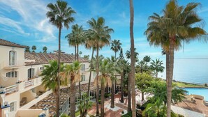 A resort with multiple-story buildings, palm trees, a swimming pool, and a view of the sea. - Grand Hotel Las Dunas, Autograph Collection (Estepona)