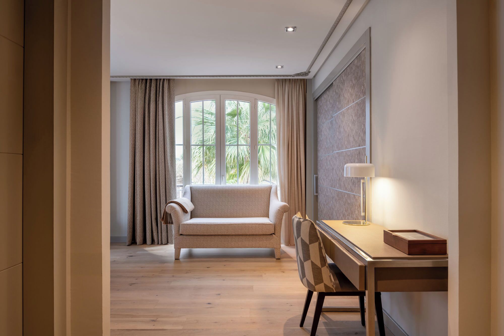 Una habitación de hotel moderna con un sofá, un escritorio y una lámpara.
