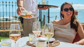 Una mesa con varias copas de vino, una botella sirviéndose y una persona sirviendo.