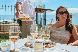 Una mesa con varias copas de vino, una botella sirviéndose y una persona sirviendo.