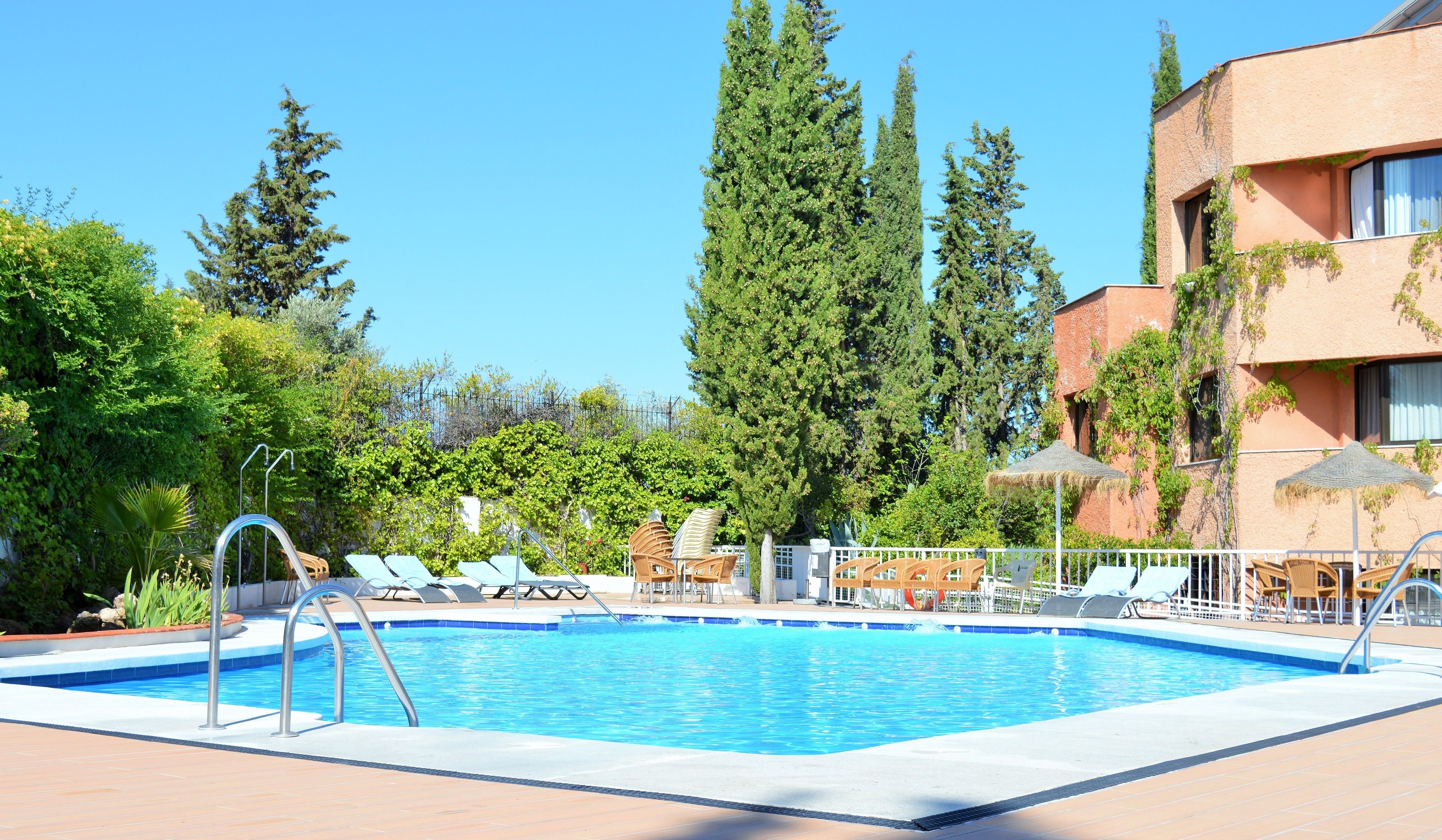Una piscina con sillas de descanso y un edificio de fachada roja.
