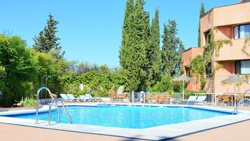 Una piscina con sillas de descanso y un edificio de fachada roja.