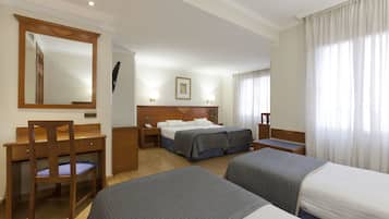 Habitación de hotel con dos camas individuales, un escritorio, una silla, un espejo y una ventana con cortinas.