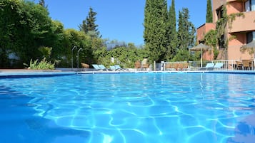 Una piscina al aire libre de temporada, sombrillas