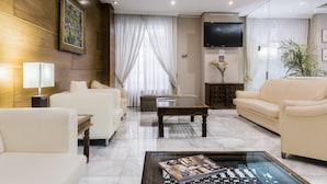 A modern living room with a sofa, armchairs, a coffee table, and a TV.