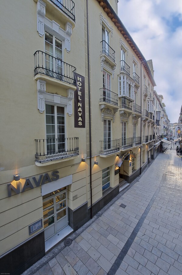 A hotel facade with balconies, a sign reading "HOTEL NAVAS," and a paved street in the background.