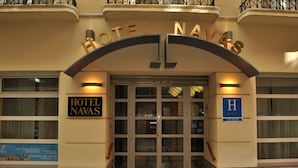 The entrance to Hotel Navas with a sign above the doors and a blue sign with an 'H' indicating the hotel.