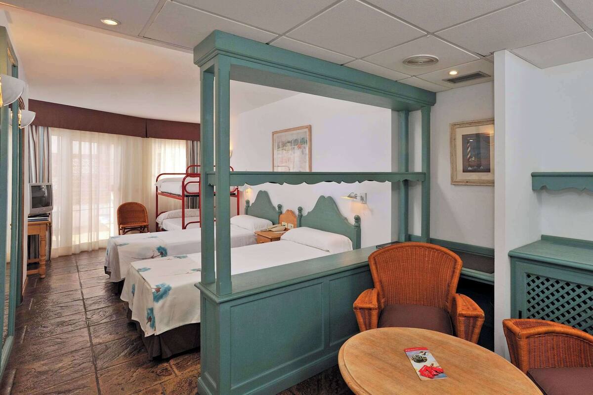 Une chambre d’hôtel avec un lit, deux chaises, une petite table et un téléviseur.