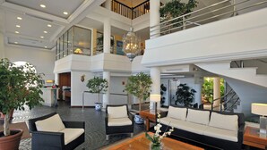 Un vestíbulo amplio con techo alto, varias zonas de estar y una escalera que conecta diferentes niveles.