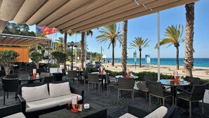 Un área de estar al aire libre con muebles de mimbre y vista a la playa.
