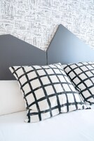 Ein Bett mit grauem Kopfteil und zwei karierten Kissen.