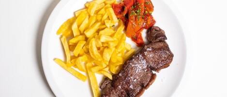 A plate with a steak, French fries, and a tomato-based dish.