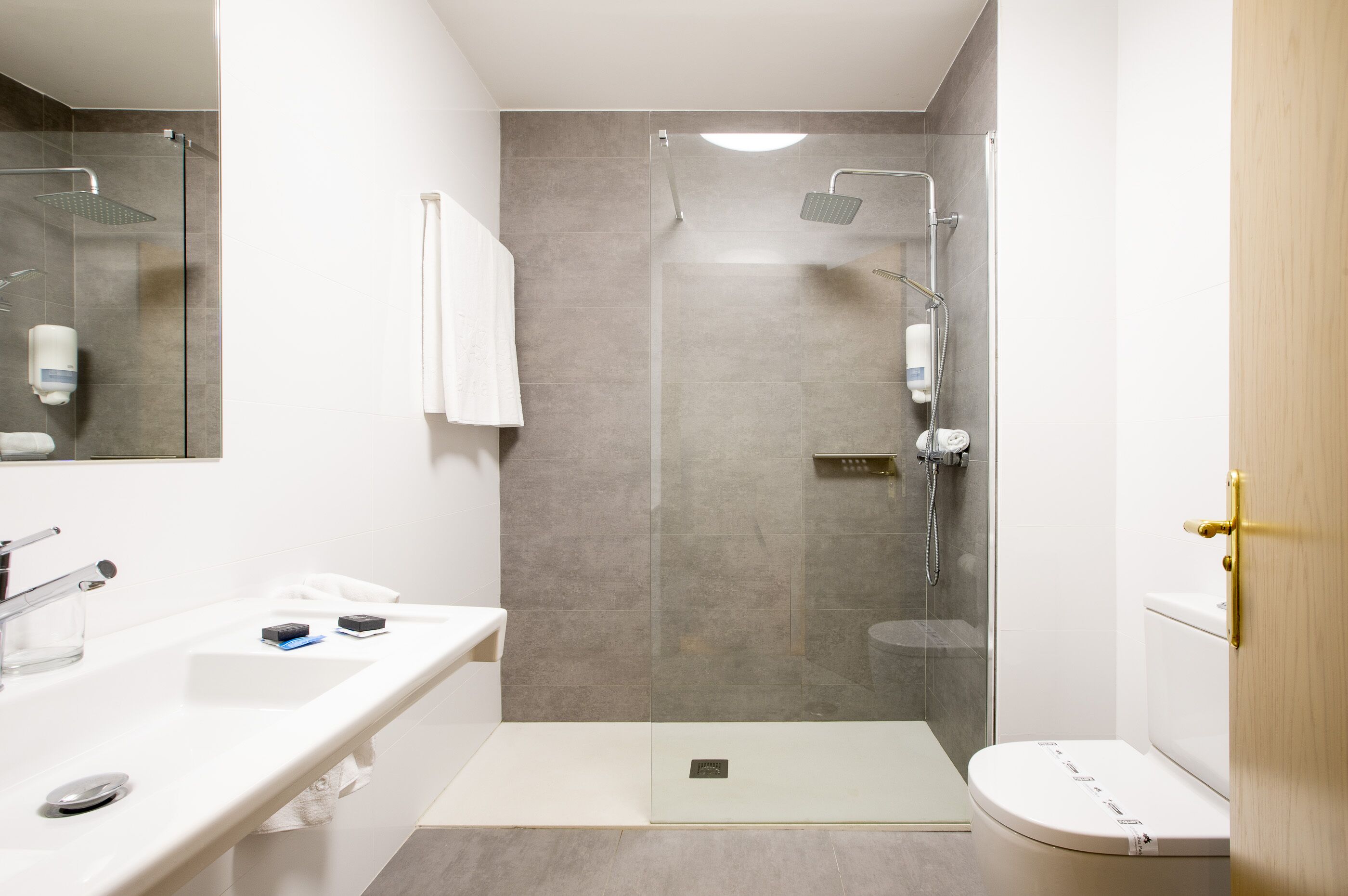 A modern bathroom with a glass-enclosed shower, a white sink, and a toilet.
