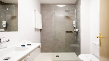 A modern bathroom with a glass-enclosed shower, a white sink, and a toilet.