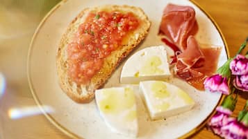 Un plato con bruschetta, jamón serrano y queso.