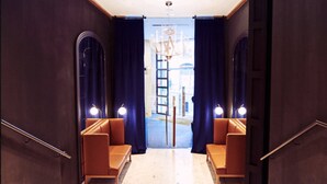 A modern interior with a staircase leading to a balcony, featuring dark walls, two seating areas, and a chandelier. - Occidental León Alfonso V (León)