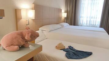 Two beds with white linens and wooden headboards, a bedside table, and wall-mounted lamps.