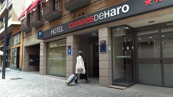 En hotellentrén med en skylt som visar texten ”HOTEL CONDES DEHARO” och en tydlig parkeringsskylt.