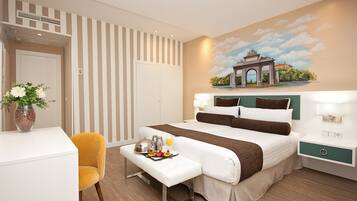 A hotel room with a bed, bedside tables, a desk, a chair, and a painting of an arch on the wall.
