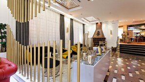 Een moderne hotel lobby met een zithoek, een receptiebalie en een open haard.