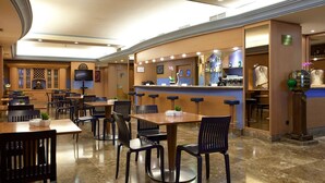 A hotel lobby with a bar area, seating arrangements, and a television screen. - Hotel Agumar Atocha (Madrid)
