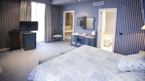 A bedroom with a large bed, a dresser, a television, and a bathroom visible through an open door. - Hotel Agumar Atocha (Madrid)