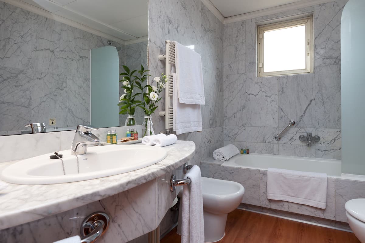 A bathroom with a marble sink, a bidet, a bathtub, and a toilet.