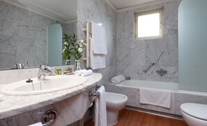 A bathroom with a marble sink, a bidet, a bathtub, and a toilet.