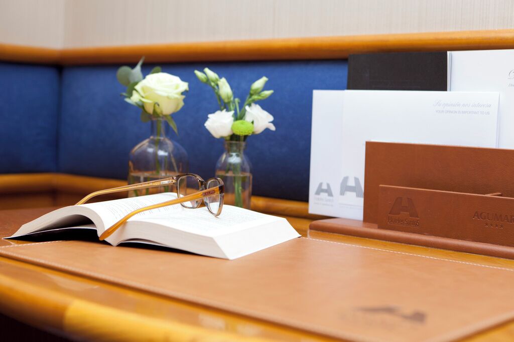 A book, glasses, and two vases with flowers on a wooden table.