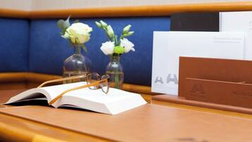 A book, glasses, and two vases with flowers on a wooden table.