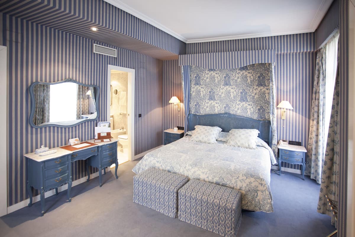 A bedroom with a large bed, a dresser, a mirror, and a nightstand.