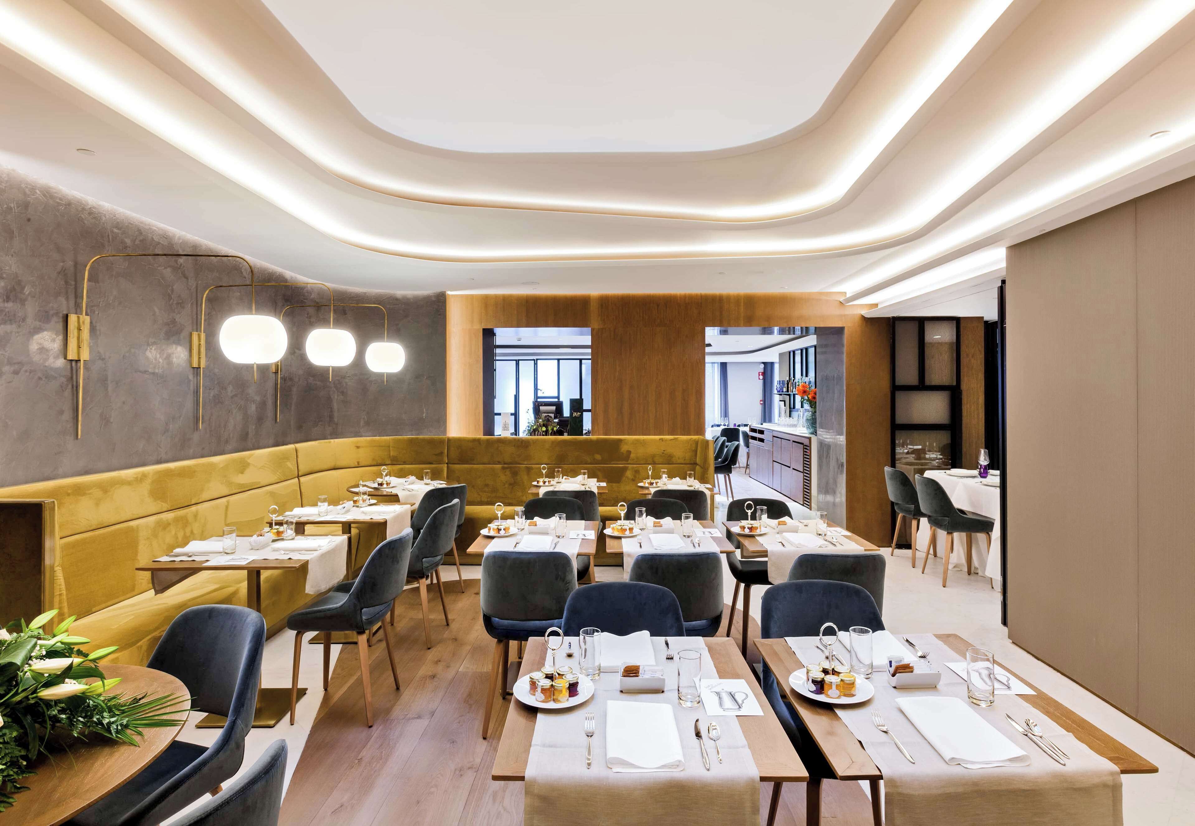 Un restaurant moderne doté d’un espace salon accueillant, de tables en bois et d’une palette de couleurs chaleureuses.