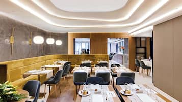 Un restaurant moderne doté d’un espace salon accueillant, de tables en bois et d’une palette de couleurs chaleureuses.