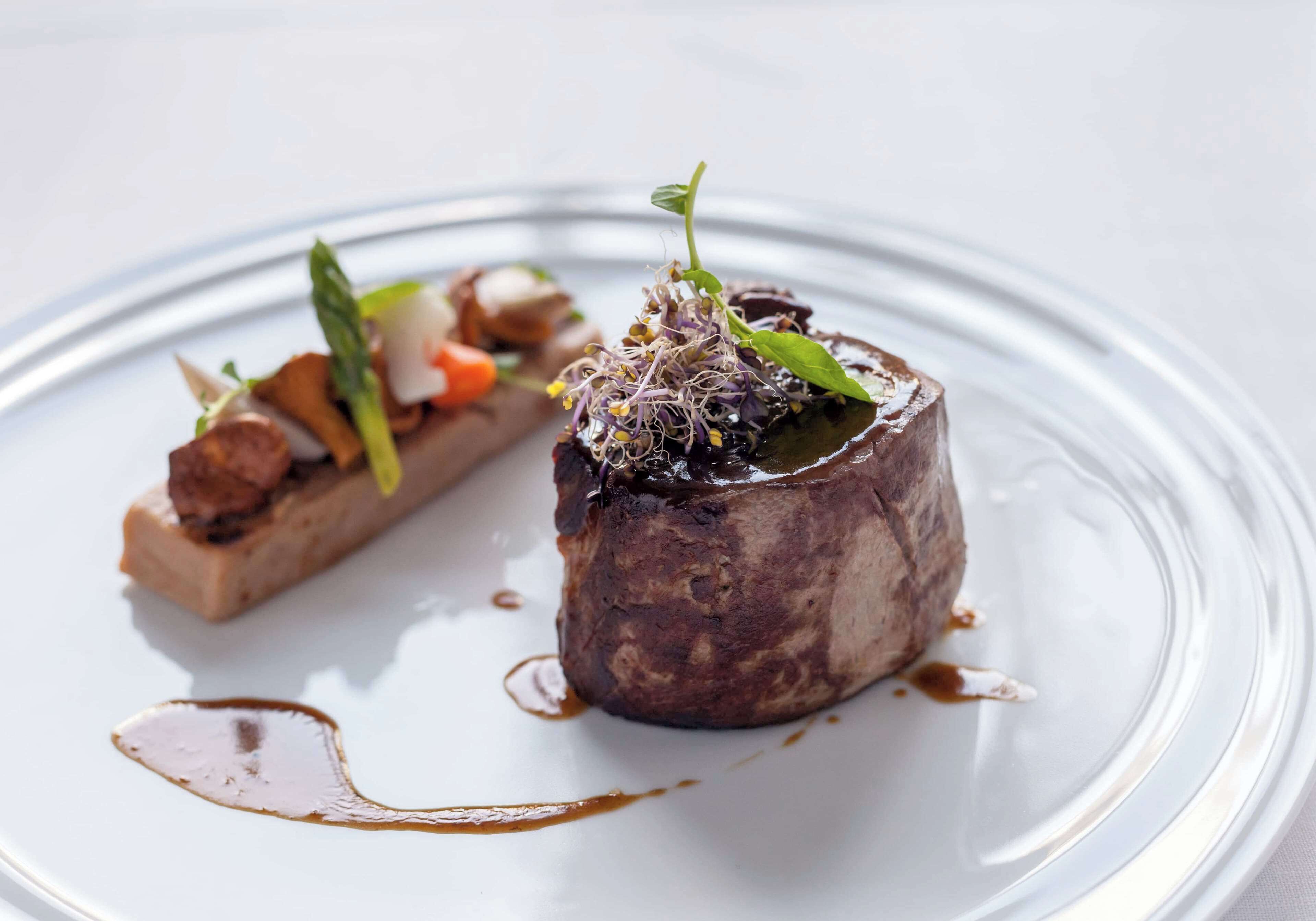 Une assiette avec un steak, des choux de Bruxelles en garniture et un accompagnement.