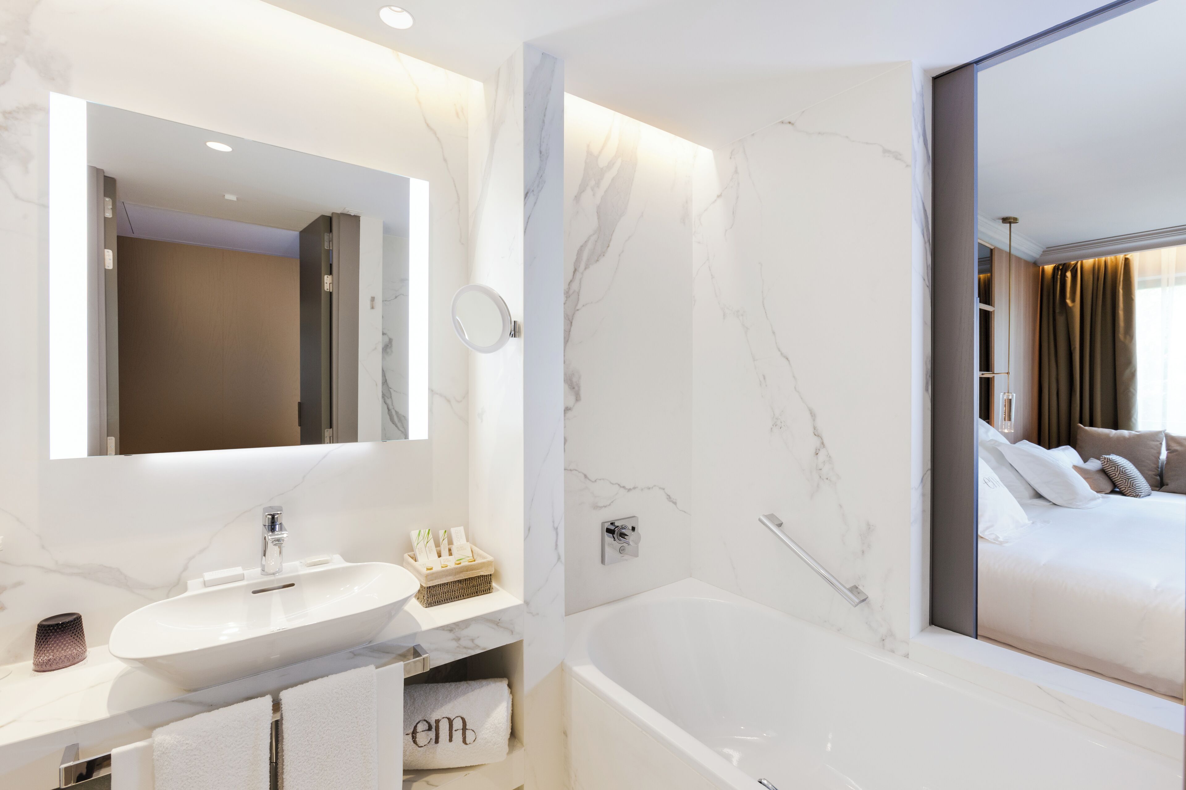 A modern bathroom with a marble sink, a large mirror, and a bathtub.