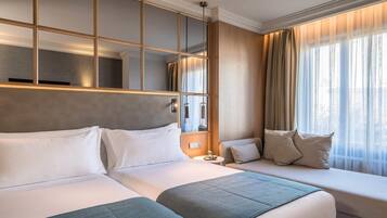 Ein Hotelzimmer mit zwei Betten, einem großen Spiegel und einem Fenster mit Vorhängen.
