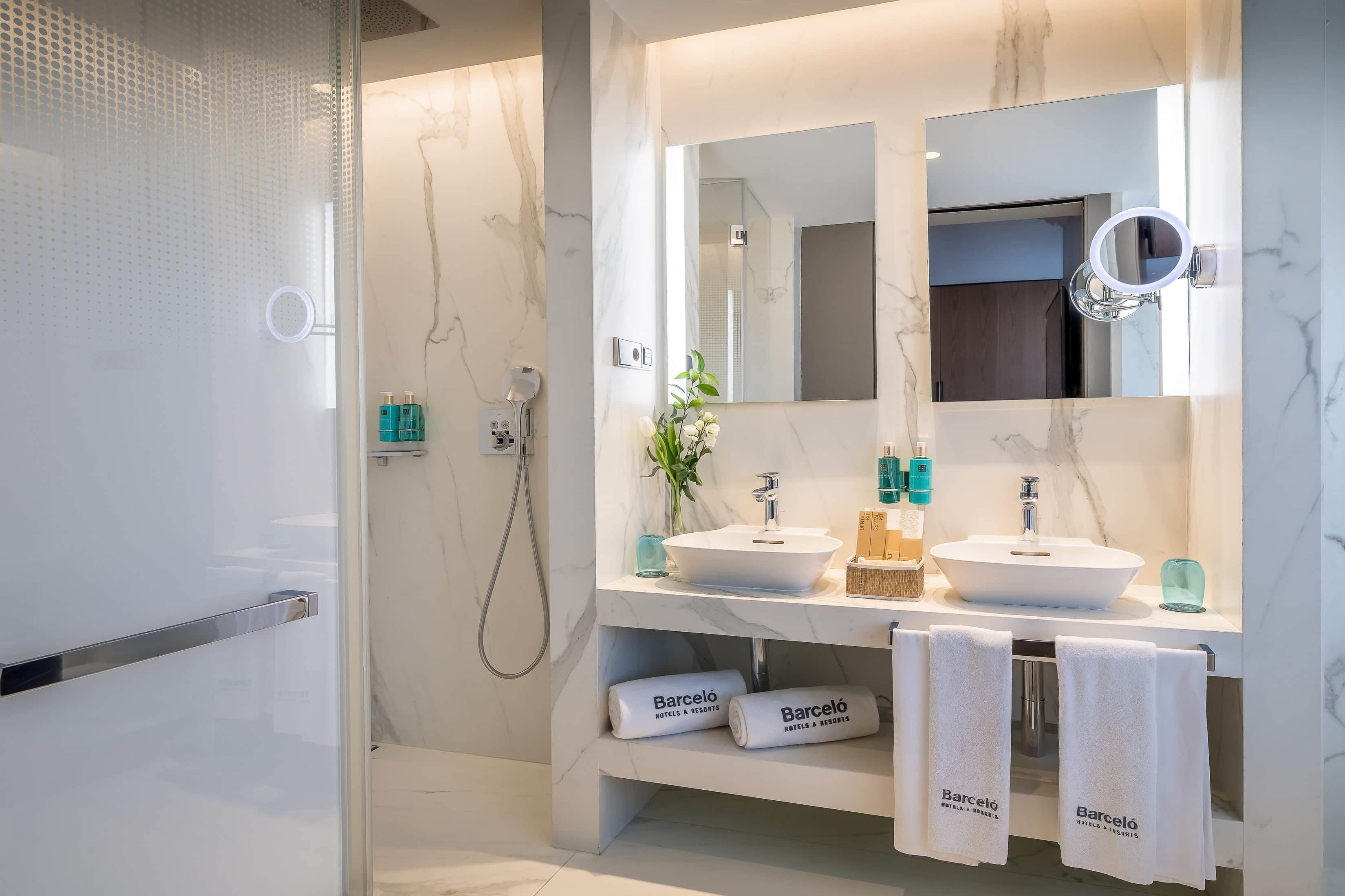 Un baño moderno con dos lavamanos, un espejo grande y una zona de ducha.