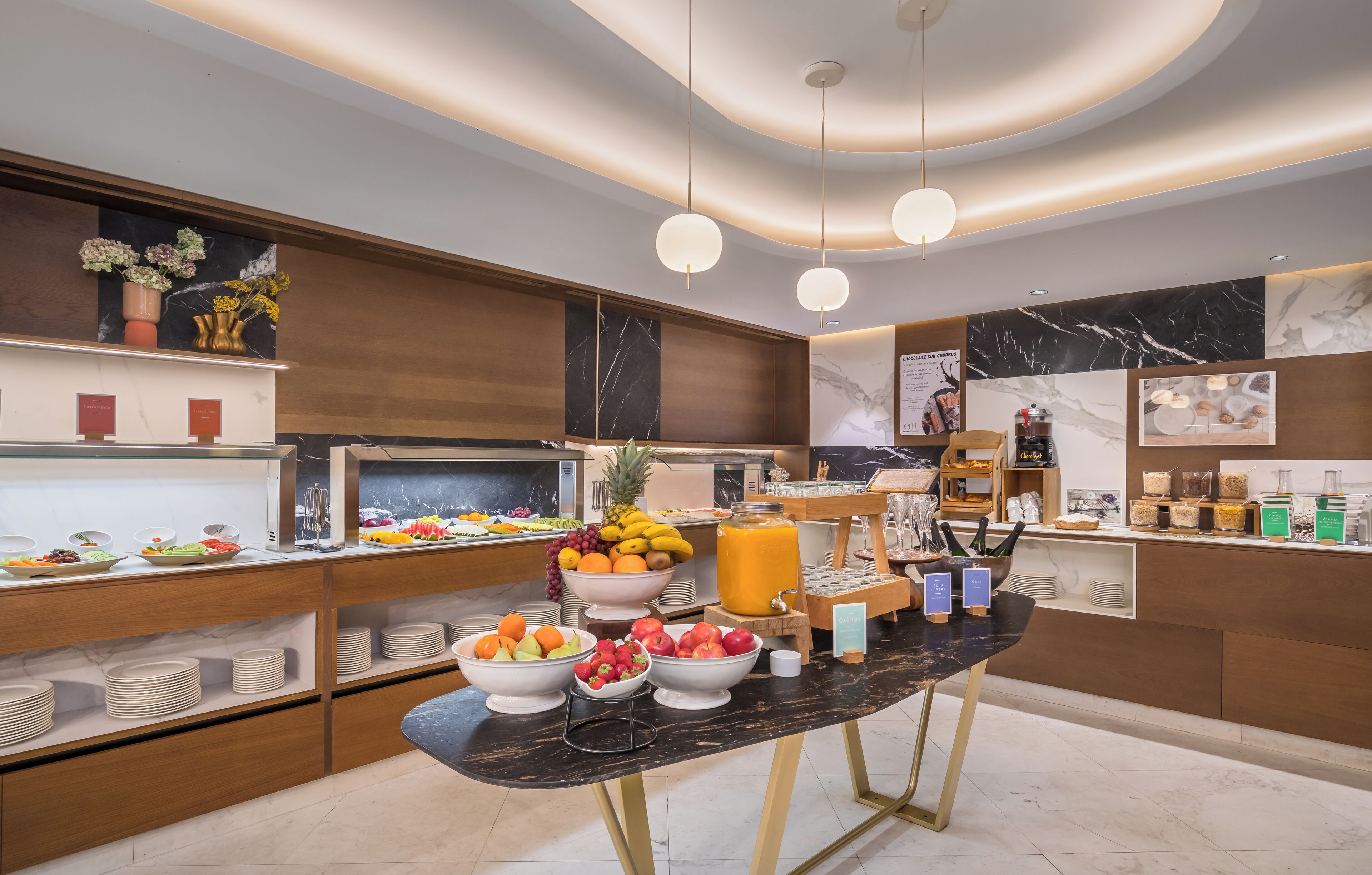 Una cocina moderna con encimeras de mármol, armarios de madera y una variedad de alimentos y bebidas.