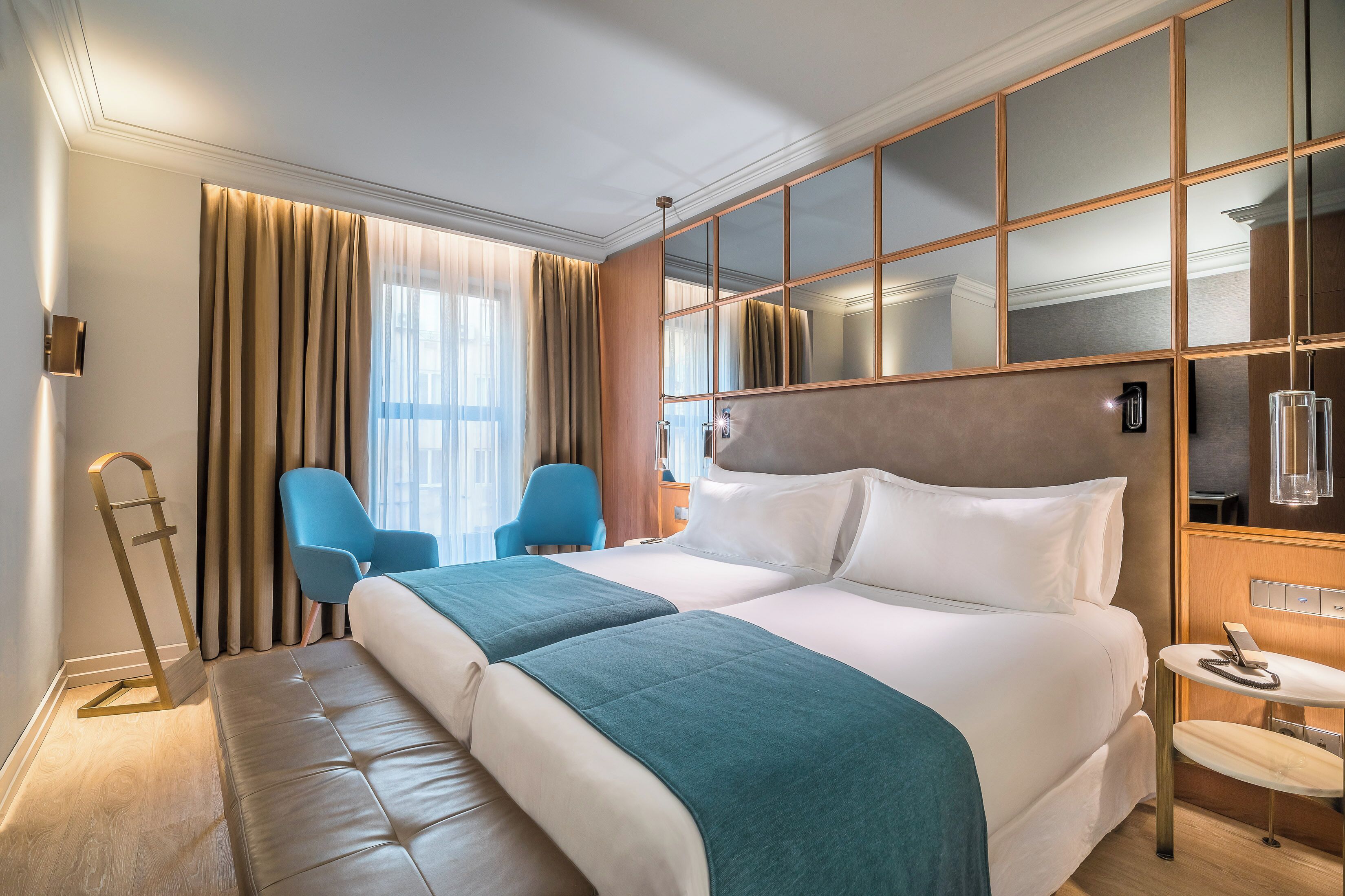 A hotel room with a large bed, a desk, a chair, and a large mirror.