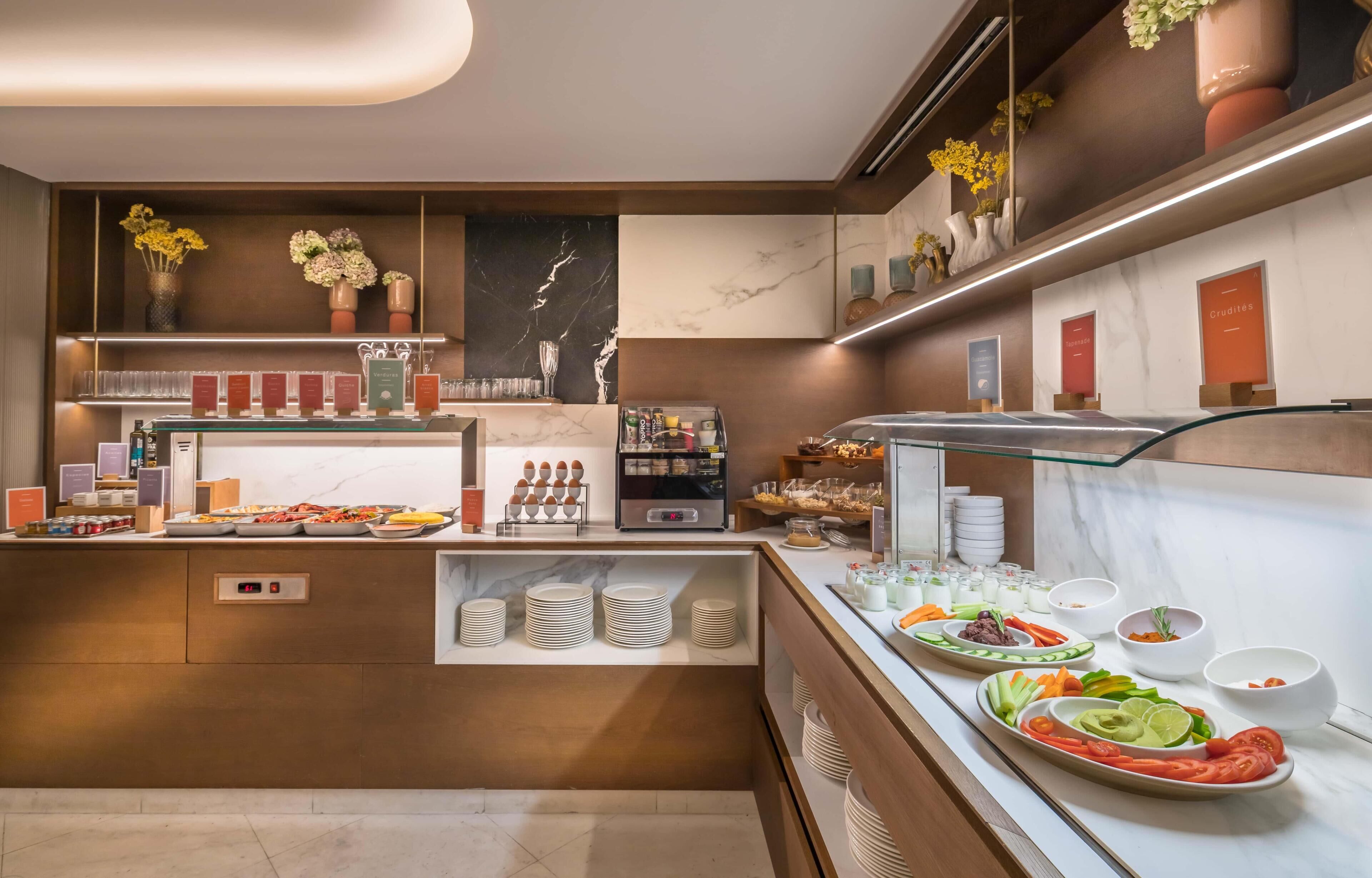 Un espace moderne pour le petit-déjeuner, avec un comptoir en marbre, de la vaisselle en verre et un choix varié de plats.