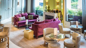 A modern lounge area with a fireplace, purple sofas, and round tables.