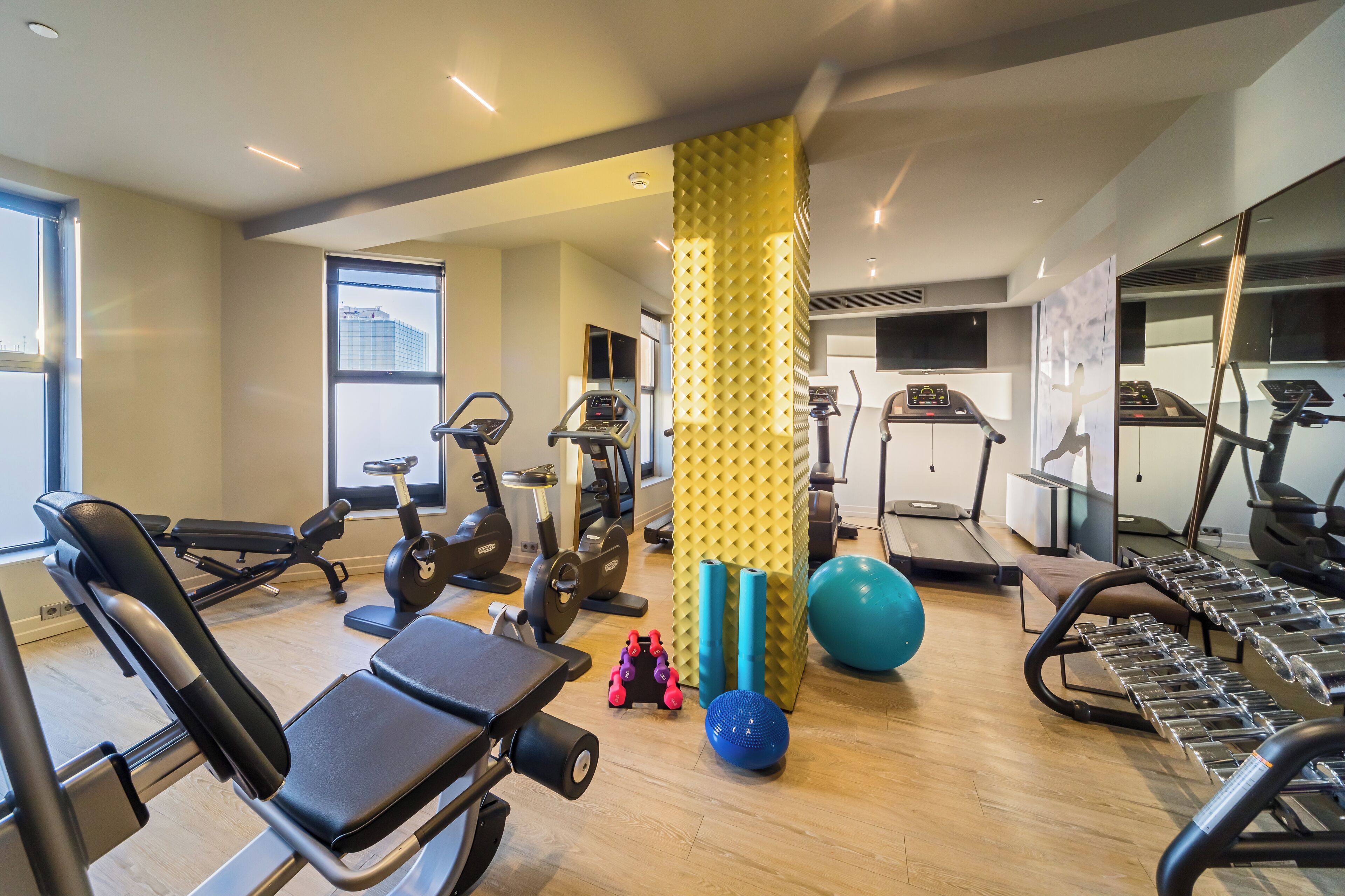 A modern gym with various exercise equipment, including treadmills, stationary bikes, and free weights.