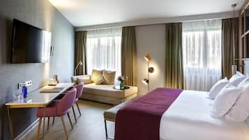 Une chambre d’hôtel moderne équipée d’un lit, d’un canapé, d’un bureau et d’une télévision.