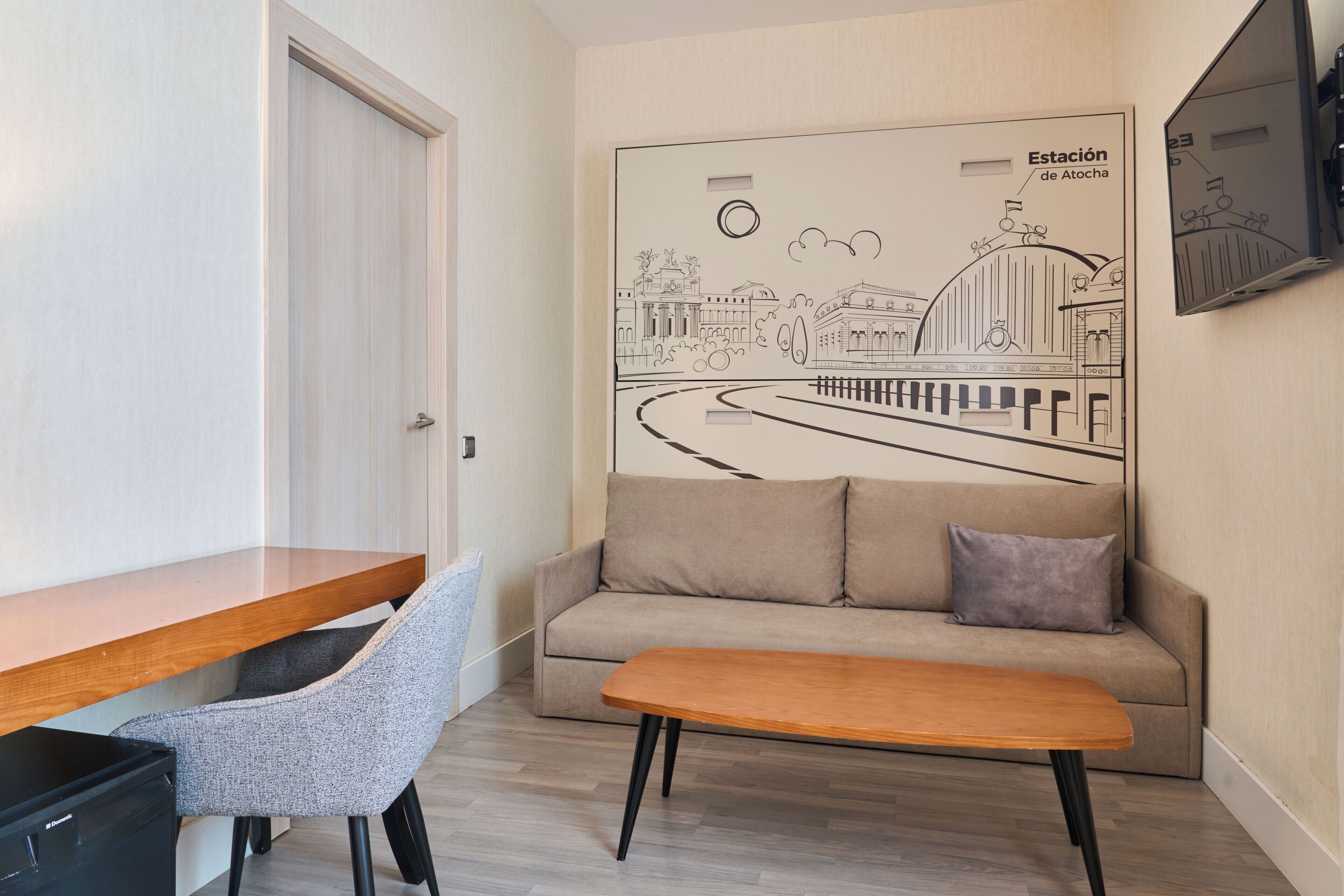 Una habitación moderna con un escritorio de madera, una silla gris, un sofá beige y un banco de madera.