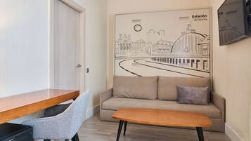 Una habitación moderna con un escritorio de madera, una silla gris, un sofá beige y un banco de madera.