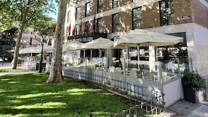 A hotel with outdoor seating, a brick facade, and a sign that reads "HOTEL PUERTA TOLEDO". - Hotel Puerta de Toledo (Madrid)