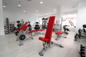 Un gimnasio con varios equipos de ejercicio, incluyendo máquinas de pesas y pesas libres.