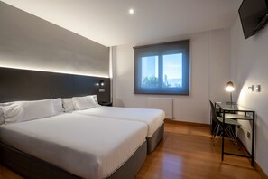 Une chambre d’hôtel moderne dotée d’un grand lit, d’un bureau avec une chaise et d’une fenêtre donnant sur la ville.