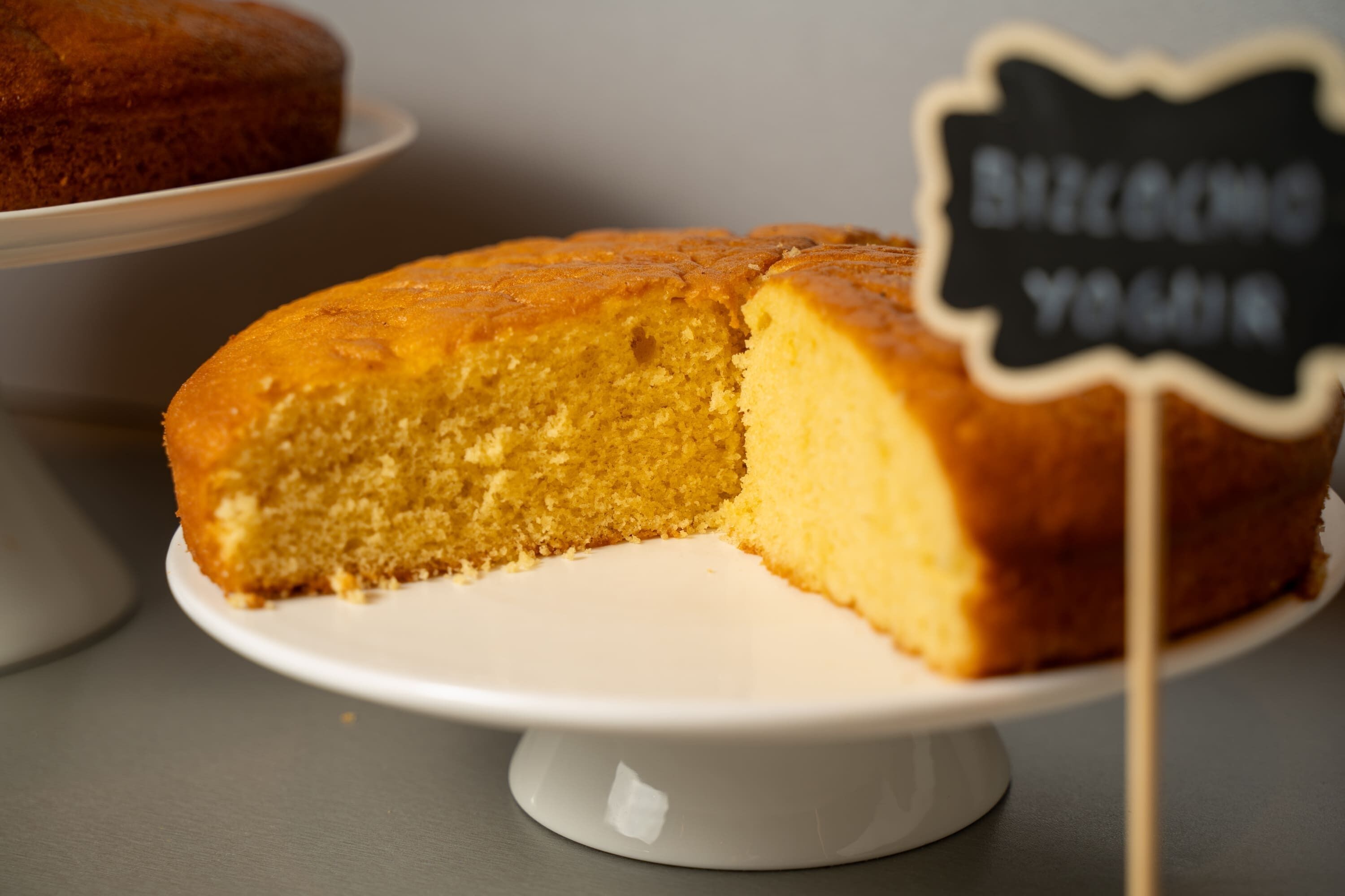 Un gâteau posé sur un présentoir blanc, avec une pancarte sur laquelle on peut lire « BIENVENUE ».